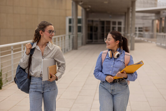 Two female students walking and talking on campus walkway