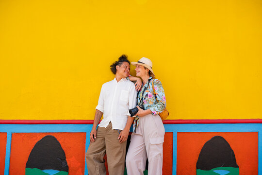 Multiethnic couple by colorful wall in Guatape, Colombia