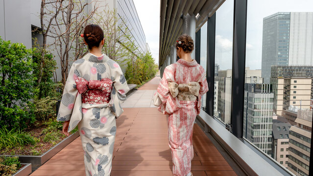 Two Japanese women in kimono walking in Tokyo near sakura