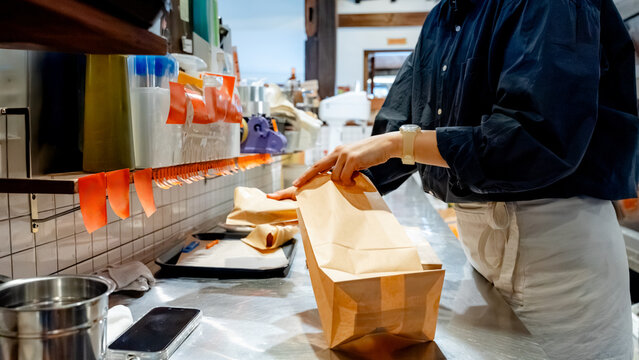 Barista packing paper bags in busy coffee shop