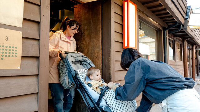 Barista assisting mother with stroller in coffee shop