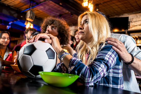 Excited sports fans celebrating goal in pub atmosphere