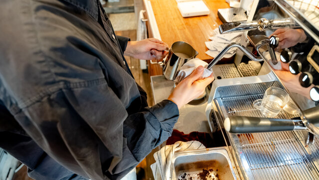 Barista cleaning coffee machine at a coffee shop