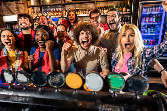 Group of friends cheering during live sports match in pub