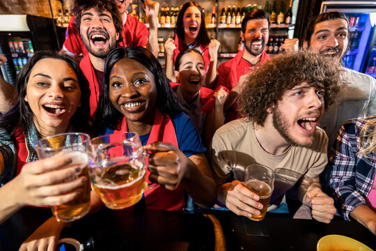 Group of friends cheering during live sports match in pub