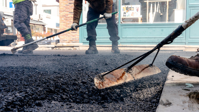 Road repair workers engaged in asphalt paving task
