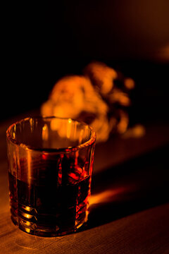 glass of whiskey by candlelight with flowers in the background, dim light
