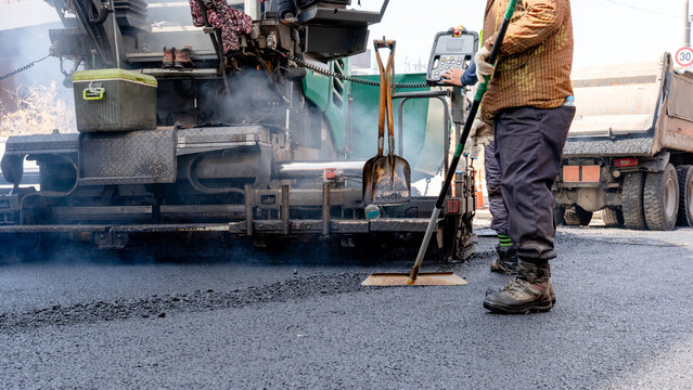 Workers paving a street with modern machinery