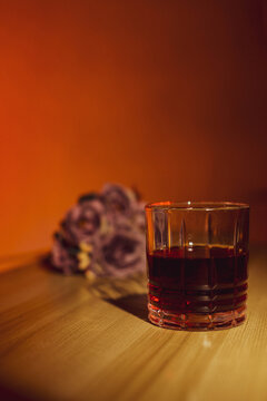 glass of whiskey by candlelight with flowers in the background, dim light