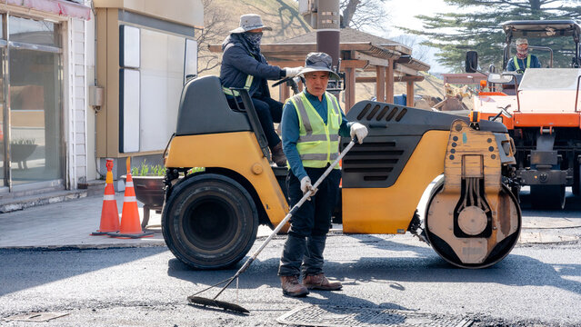 Workers paving a street with asphalt machinery in South Korea
