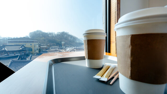 Coffee cups on cafe table by window with city view
