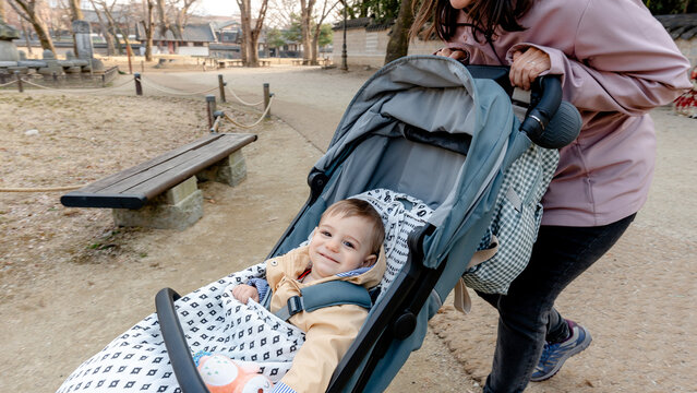 Mother pushing baby stroller during family travel walk