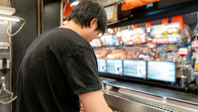 Back view of Taiwanese street vendor working at night food market
