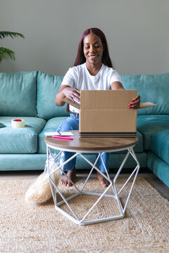 Black woman packing a parcel for secondhand app sale at home