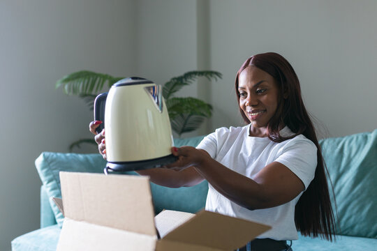 Black woman selling a kettle on a secondhand app at home