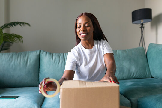 Black woman packing thrift sale order for secondhand app