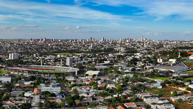 General drone view of the city of Cascavel, western region of Parana, showing the buildings, houses, and wooded areas on a slightly sunny day.