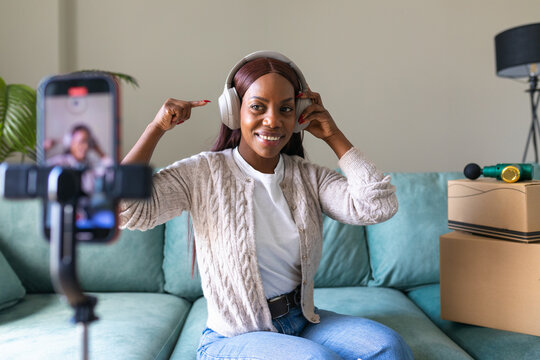 Black woman selling secondhand headphones online at home