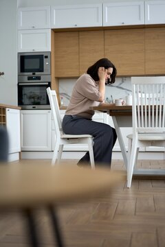 Stressed Woman Sitting Alone at Kitchen Table