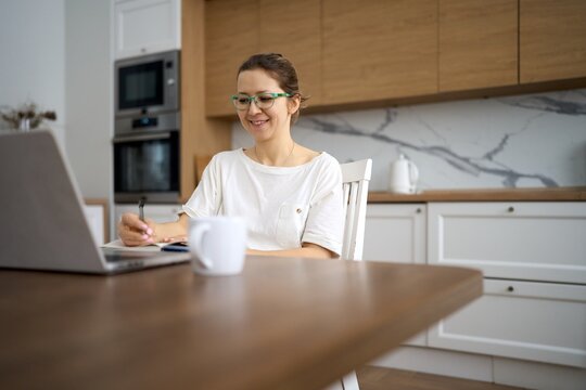 Cheerful Woman Working Remotely in Modern Kitchen