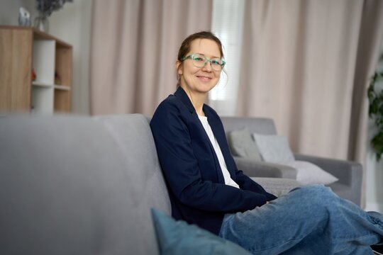 Smiling professional woman relaxing on sofa in modern living room