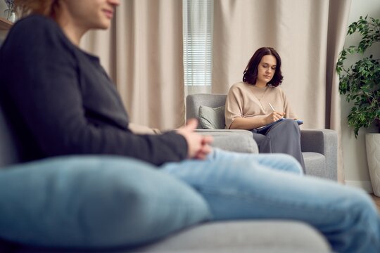 Therapist writing notes while listening to client in session