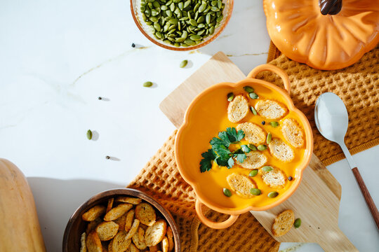 Creamy pumpkin soup with croutons on marble background