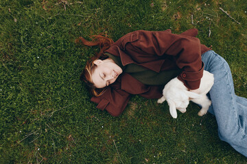 Obraz premium A girl lying on green grass outdoors with a goat kid by her side, a calm lifestyle moment showing companionship, gentle affection, and simple wholesome outdoor life.