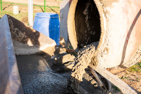 Wet concrete pouring from mixer at outdoor construction site