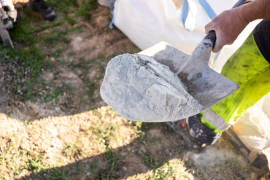 Worker mixing concrete mortar with shovel at outdoor site
