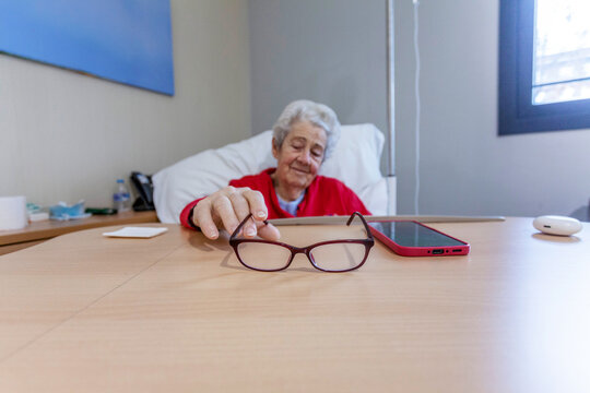 Senior patient in hospital room reaching for glasses