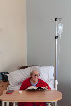 Elderly patient reading in hospital room setting