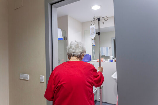 Elderly patient with IV pole in hospital hallway