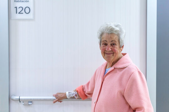 Elderly patient in hospital hallway with supportive smile