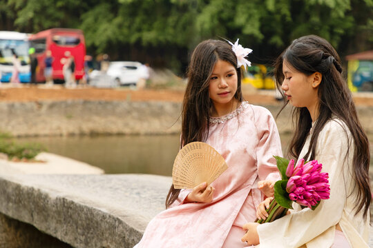 Young Vietnamese teenagers in traditional dress by temple