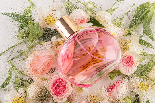 Perfume bottle with water drops on floral background