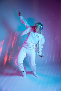 Futuristic woman dancing in neon light with headphone