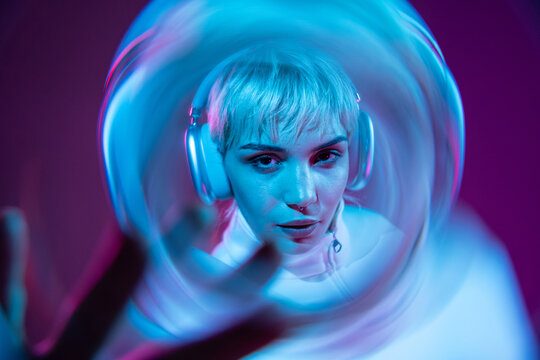 Futuristic woman in neon light with visor and headphones