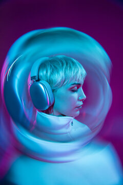 Futuristic woman in neon helmet listening to music