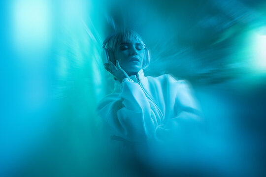 Futuristic woman in teal blur listening with headphones