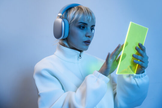 Futuristic woman using glowing translucent tablet with headphones