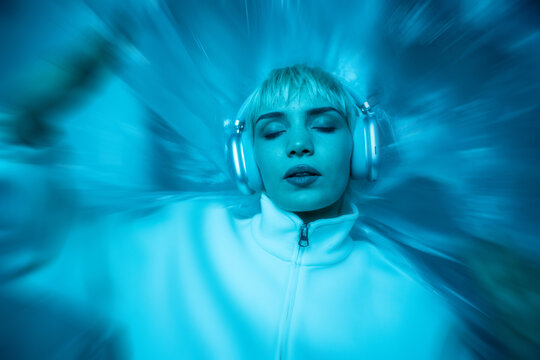 Futuristic woman in headphones with neon blue motion blur