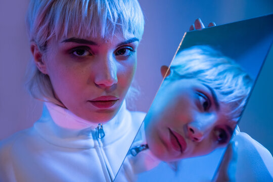 Futuristic woman with platinum hair holding a mirror portrait