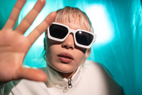 Futuristic woman in white sunglasses with neon backdrop