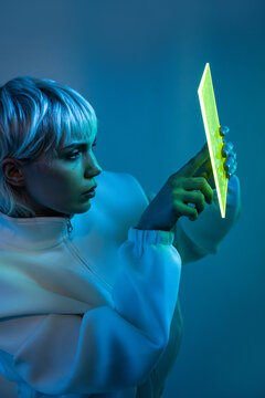 Futuristic woman using glowing touchscreen in neon light