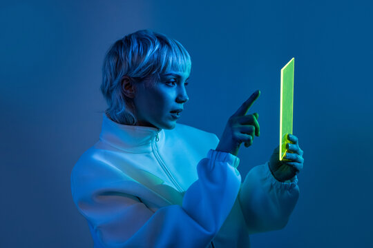 Futuristic woman using neon tablet in blue light portrait