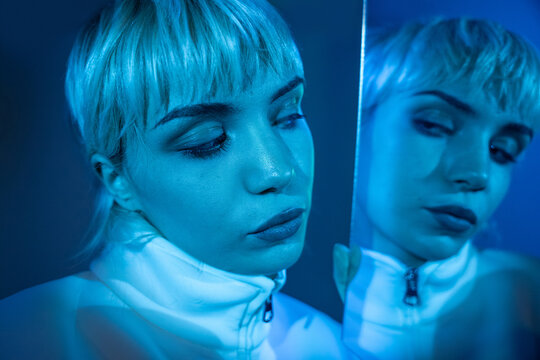 Futuristic woman portrait with mirror reflection in blue light