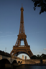 Obraz premium Eiffel Tower in Paris at sunset with warm evening light and clear blue sky