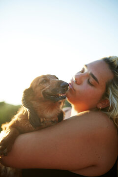 Woman hugging dog at sunset in warm golden light outdoors