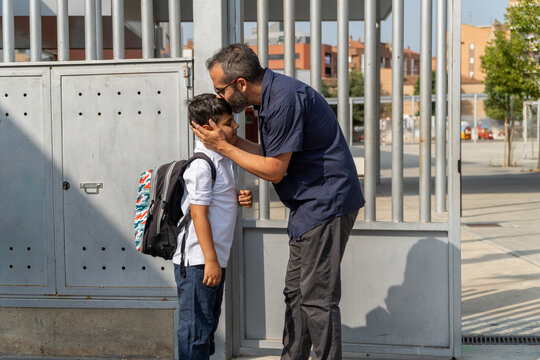 Father bidding farewell to son at school gate